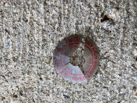 2015 Ford F-550 - A broken sticker with red text is adhered to a textured concrete surface.