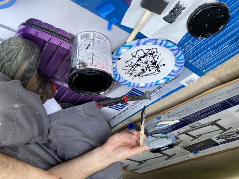 2015 Ford F-550 - A person is engaged in painting with black paint, surrounded by art supplies and a purple suitcase.