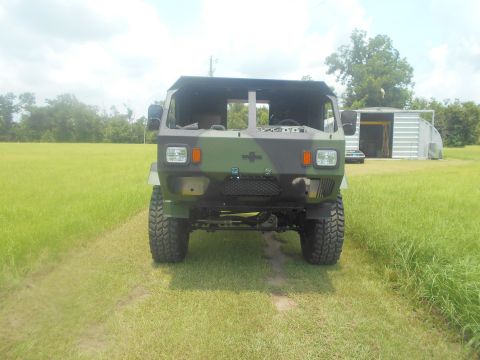 1992 Ford Bronco - This military truck is parked in a grassy area with a shed in the background.