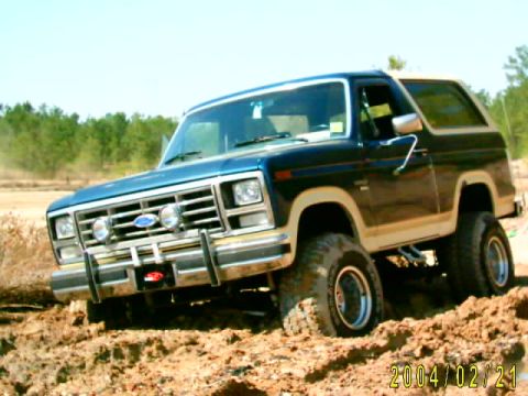 1985 Ford Bronco - This lifted Ford Bronco navigates a challenging off-road terrain with large tires.