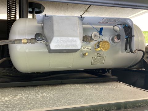 2015 Ford F-550 - A propane tank is visible, mounted beneath a vehicle, fill and vapor ports and various fittings.
