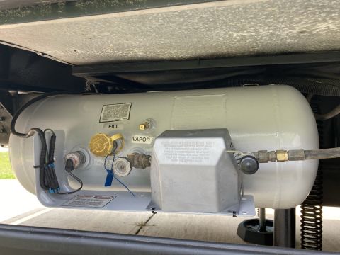 2015 Ford F-550 - Close-up of a propane tank showing fill and vapor ports, along with a regulator housing.