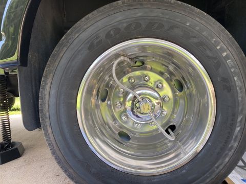 2015 Ford F-550 - Close-up of a vehicle's tire and chrome wheel assembly, with a jack visible supporting the vehicle.