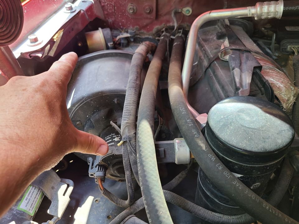 Close-up of a vehicle's blower motor and AC lines under the hood