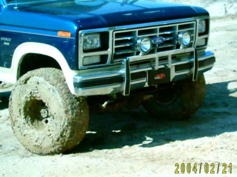 1985 Ford Bronco - This 1985 Ford Bronco is shown with its front end covered in mud and large tires.