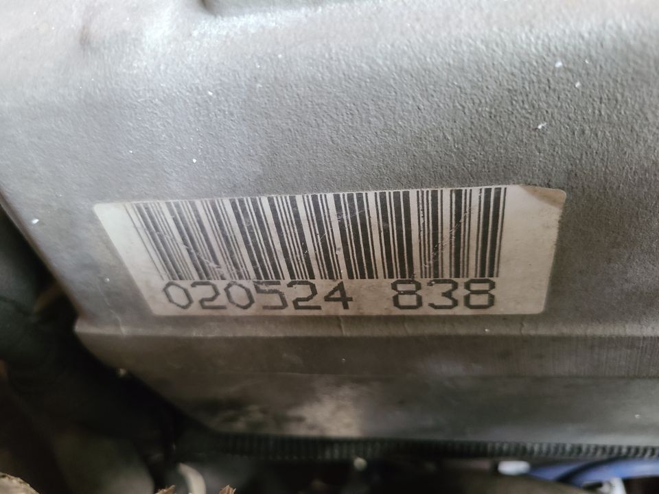 Close-up of a metal part with a barcode sticker showing numbers 020524 838