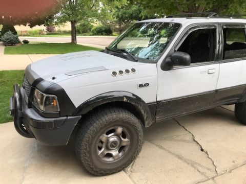 2000 Ford Explorer - A white and black 1995 Ford Explorer is shown from the front three-quarter view, parked on a concrete driveway.