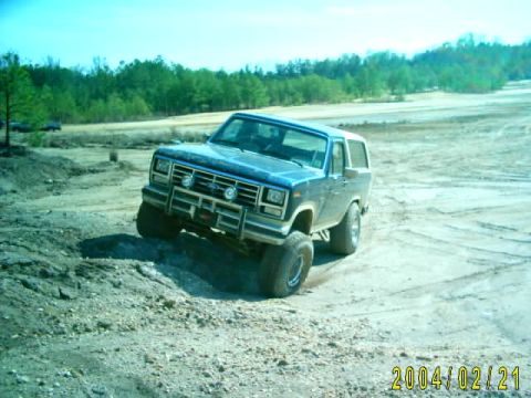 1985 Ford Bronco - This 1985 Ford Bronco is navigating a dirt track with a wooded area behind it.