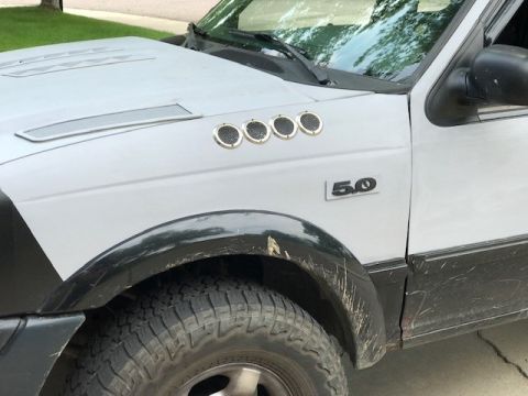 2000 Ford Explorer - This image shows the side fender of a white SUV, four circular vents and a '5.0' badge, indicating a possible engine size.