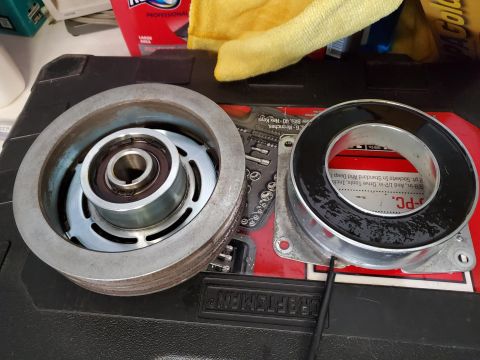 1996 Ford Bronco - Two parts of an AC compressor clutch assembly are laid out on a toolbox, with tools visible in the background.