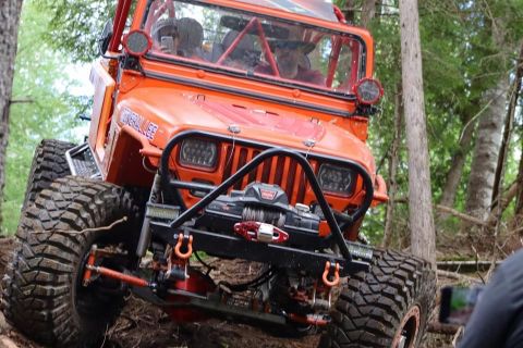1992 Jeep Wrangler - This modified 1992 Jeep Wrangler navigates a wooded trail with its distinctive orange paint and off-road modifications.