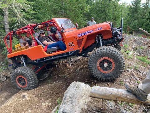 1992 Jeep Wrangler - An orange off-road Jeep with a roll cage and 'GENERAL LEE' decal is seen traversing a challenging rocky terrain.