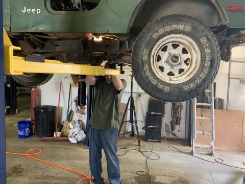 1979 Jeep CJ5 - A mechanic works on a green 1979 Jeep CJ5 being serviced on a lift.