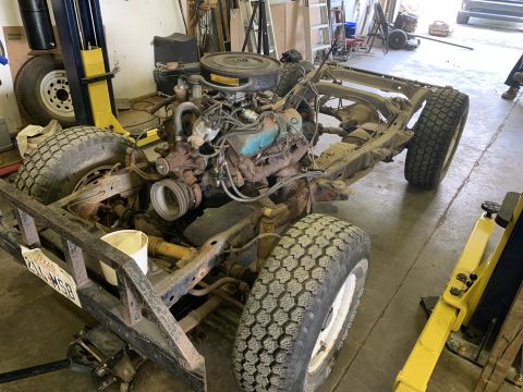 1979 Jeep CJ5 - The chassis and engine of a 1979 Jeep CJ5 are visible, with tires mounted and the vehicle supported by jacks.