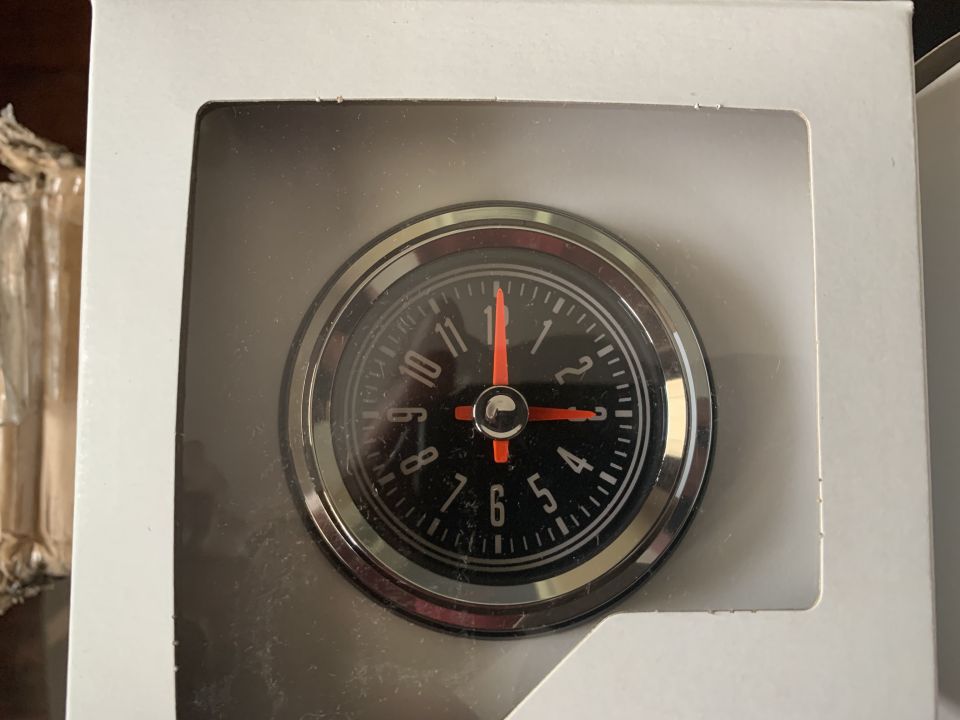 Black car clock with chrome bezel and red hands