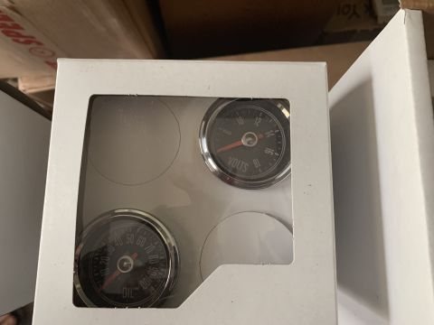 1979 Jeep CJ5 - A set of automotive gauges, including a voltmeter and oil pressure gauge, packaged for sale.