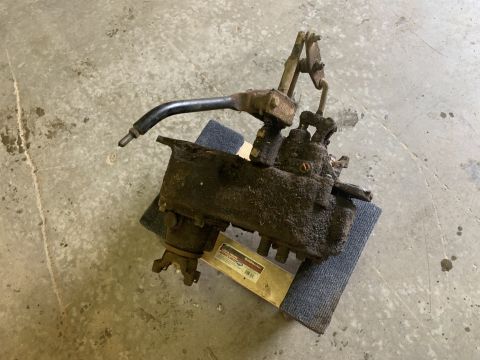 1979 Jeep CJ5 - Transfer case with linkage, resting on a blue mat over a yellow jack on a concrete floor.