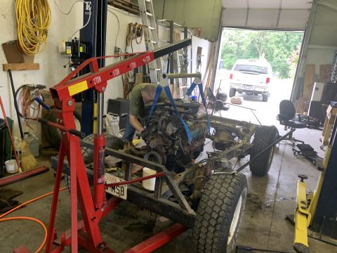 1979 Jeep CJ5 - A mechanic uses an engine hoist to remove the engine from a Jeep CJ frame inside a garage.