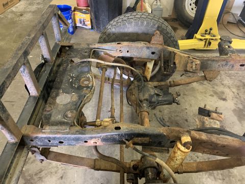 1979 Jeep CJ5 - The frame of a Jeep CJ shows significant rust and wear, with suspension parts and a tire visible.