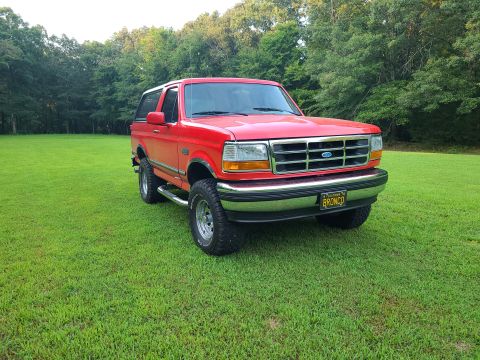 1995 Ford Bronco - This 1995 Ford Bronco is parked on a grassy area with trees in the background.