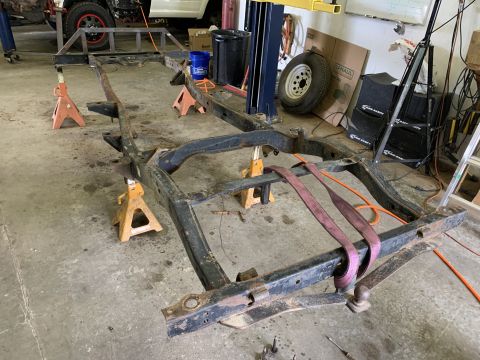 1979 Jeep CJ5 - A vehicle frame is supported by jack stands in a garage setting.
