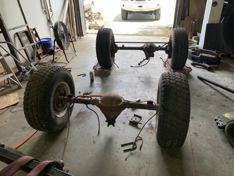 Jeep CJ5 front and rear axles with wheels, disassembled in a garage