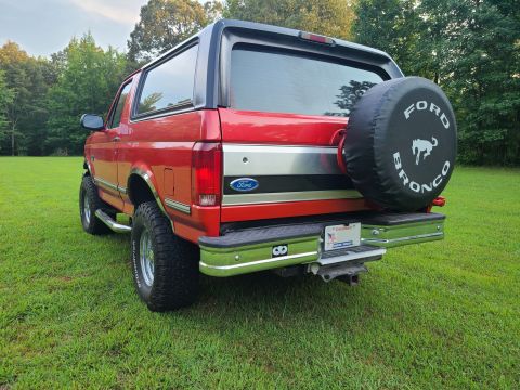 1995 Ford Bronco - Rear view of a red 1995 Ford Bronco, showing the spare tire and chrome bumper.