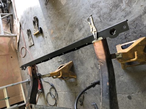 1979 Jeep CJ5 - A metal frame part is secured with clamps on jack stands, with tools and gloves nearby.