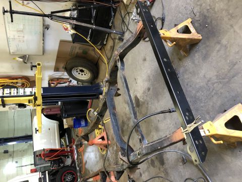 1979 Jeep CJ5 - The frame of a vehicle is disassembled and supported by jack stands in a workshop setting.