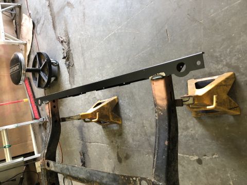 1979 Jeep CJ5 - Vehicle frame section supported by jack stands, with a metal bar overhead and a Craftsman tool.