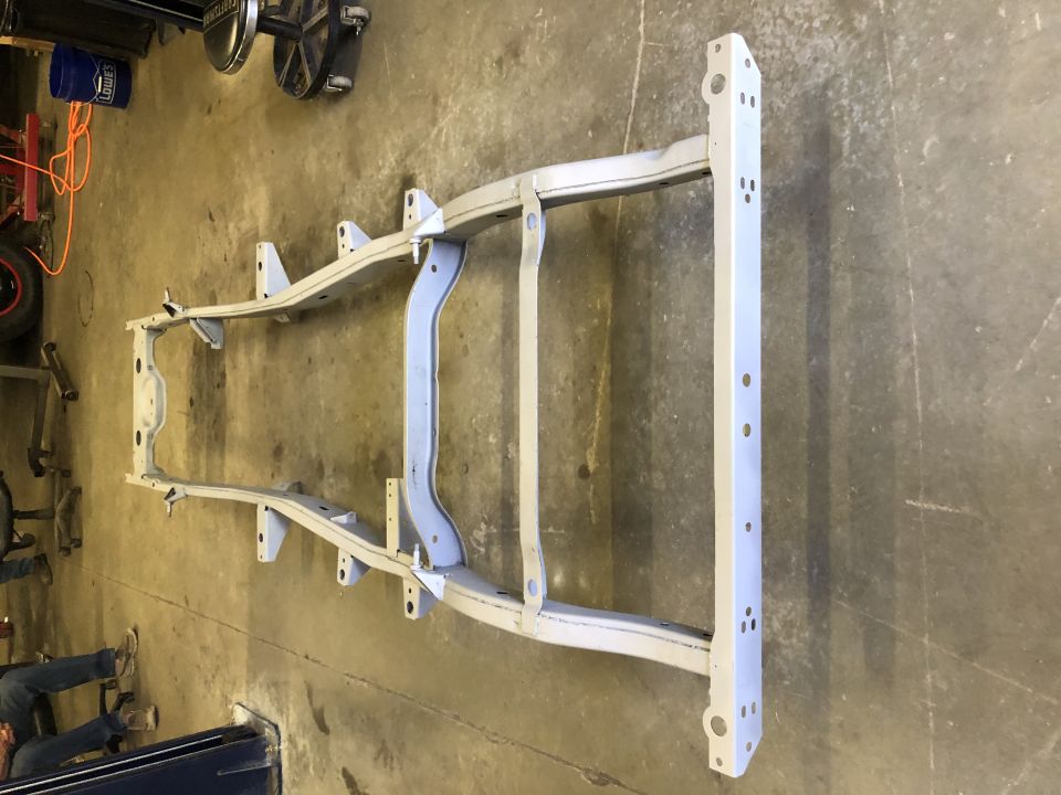 vehicle frame on concrete floor, some tools in background
