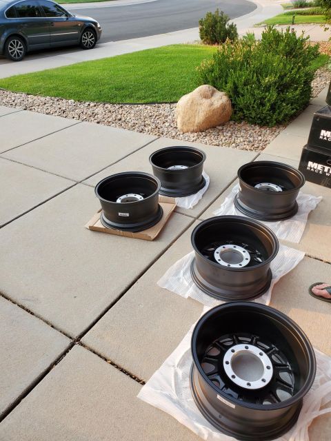 1996 Ford Bronco - Four new black wheels are ready for installation on a vehicle.