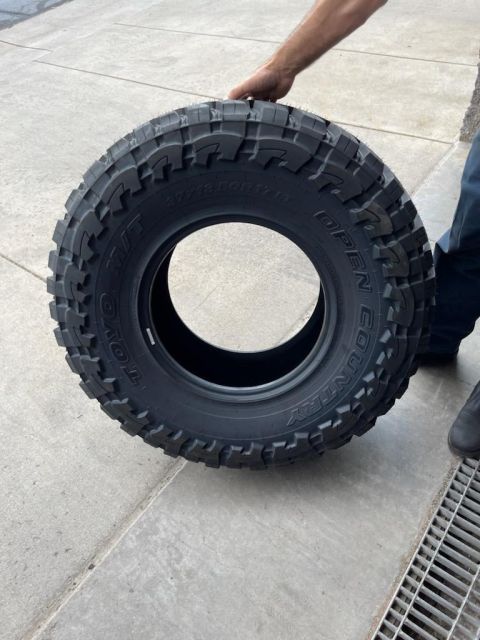 1996 Ford Bronco - A person holds a Toyo Open Country A/T tire, which is a part for a vehicle.