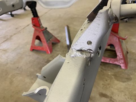 1979 Jeep CJ5 - Close-up of a vehicle frame section, supported by red jack stands, revealing welded repairs and drilled holes.
