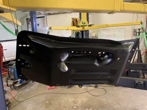 1979 Jeep CJ5 - A black metal panel is suspended by straps from a workshop lift, with a welding machine visible in the background.