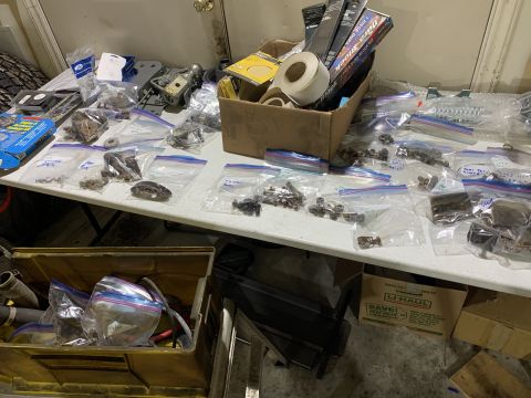 1979 Jeep CJ5 - Table covered with many small vehicle parts organized in plastic bags and boxes.