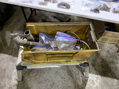 1979 Jeep CJ5 - Various automotive parts are organized in plastic bags within a yellow toolbox, resting on a metal stand.