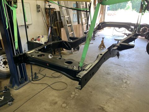 1979 Jeep CJ5 - The chassis of a vehicle is suspended on a lift, likely for repair or restoration work.