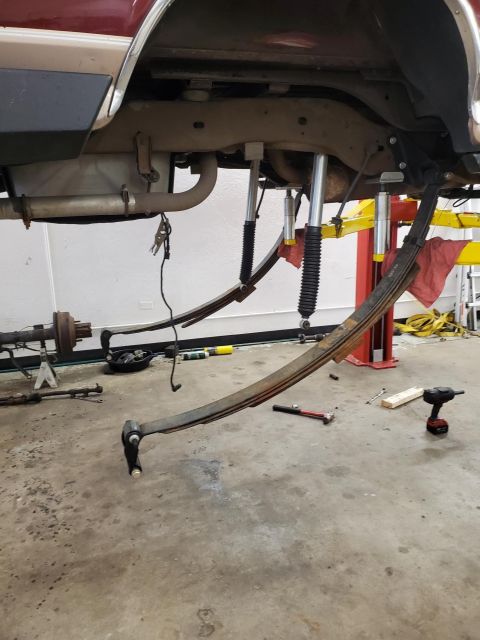 1996 Ford Bronco - The rear suspension of a vehicle is shown disassembled, with leaf springs and shocks removed for repair.
