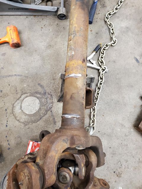 1996 Ford Bronco - Close-up of a rusty driveshaft component, likely from an older vehicle, resting on a workshop floor.