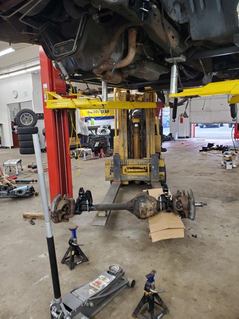 1996 Ford Bronco - Front axle assembly removed from a vehicle and supported by jack stands in a workshop.