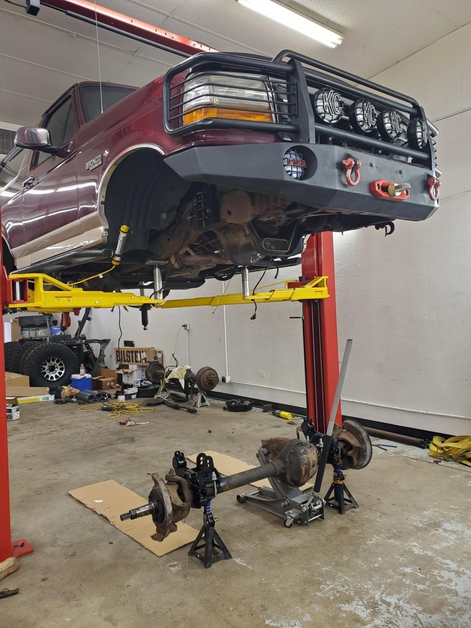 1996 Ford Bronco on a lift with its front axle removed and placed on jack stands