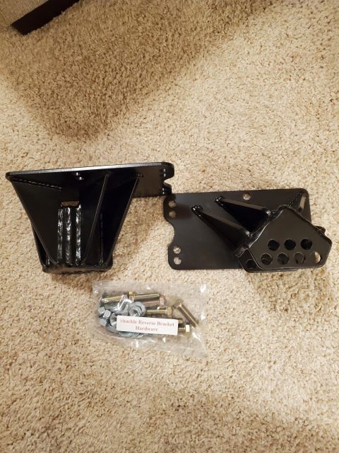 1996 Ford Bronco - A shackle reverse bracket kit with hardware is laid out on a carpeted surface.