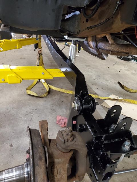 1996 Ford Bronco - Close-up of a custom suspension linkage being installed on a vehicle frame, likely for an off-road modification.