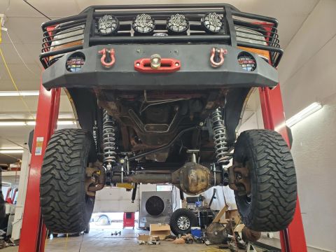 1996 Ford Bronco - This heavily modified SUV is elevated on a lift, revealing its robust suspension and off-road tires.