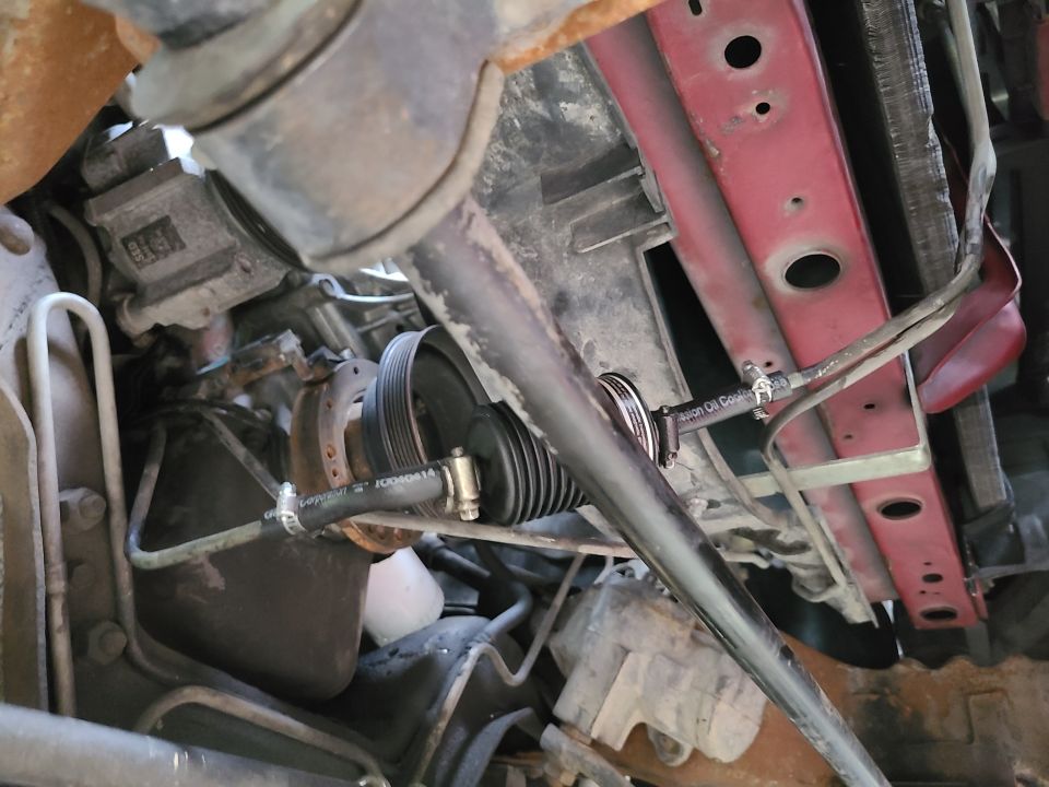 Close-up of a vehicle's power steering pump and pulley assembly with hoses attached