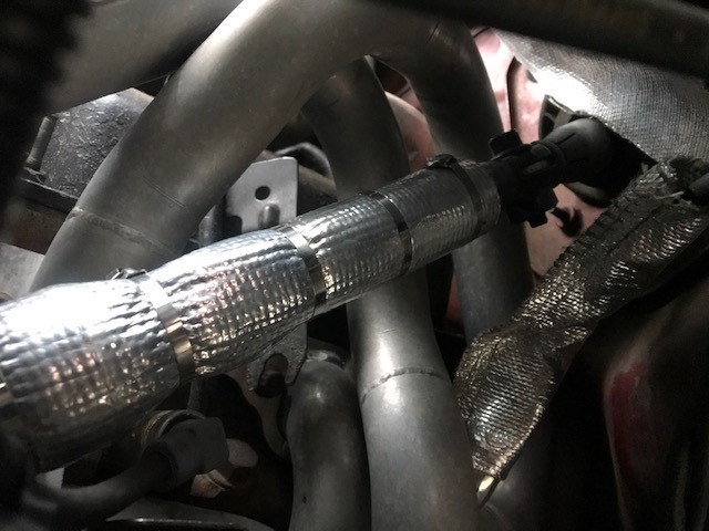 Close-up of silver exhaust pipes with heat shielding and black connectors