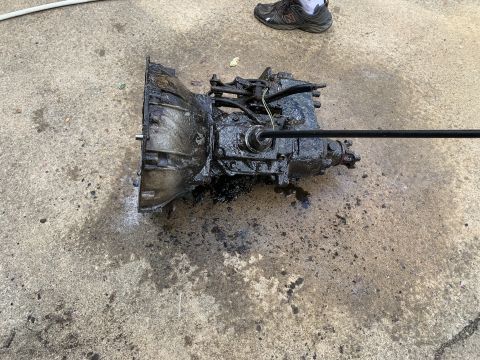 1979 Jeep CJ5 - A heavily soiled transmission assembly rests on a concrete surface, likely awaiting cleaning or repair.