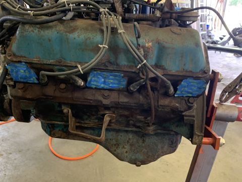 1979 Jeep CJ5 - Close-up view of a rusty engine block, likely from an older vehicle, with visible spark plug wires and blue tape applied to the spark plug…