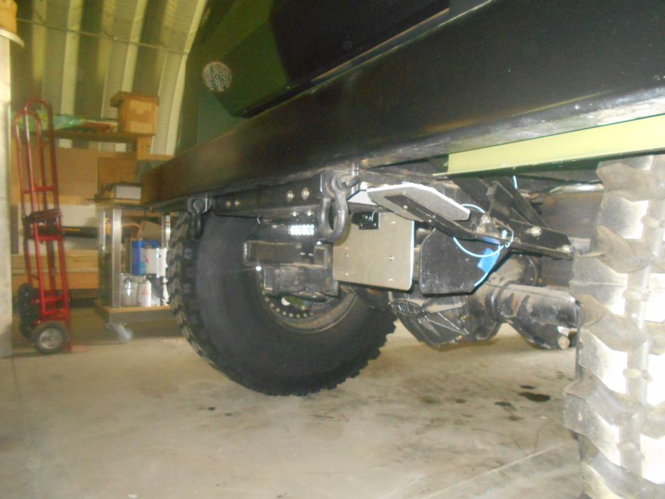 Rear axle and tire of a large vehicle, showing suspension components and a tow hitch receiver